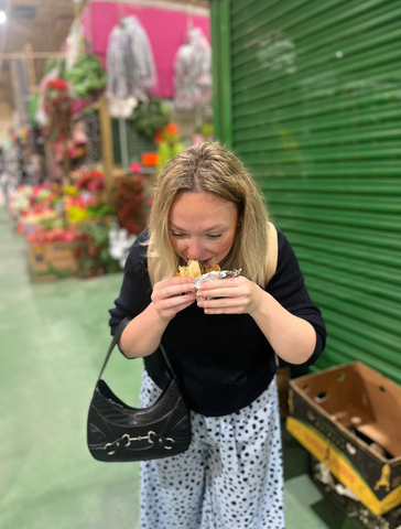 Blonde woman eating a sandwich in Leeds market on the food tour