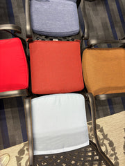 top-down photo of 5 different color dining cushions on black weave aluminum dining chairs.