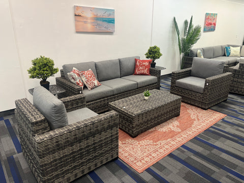 grey wicker sectional couch, club chair, and coffee table in on orange throw rug