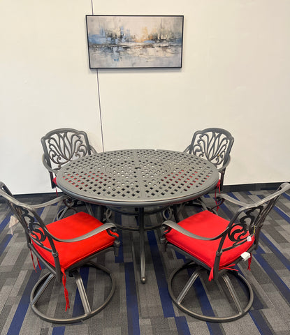 Silver Metal circular dining table, surrounded by 4 with elegant flower pattern chairs with bright red cushions.