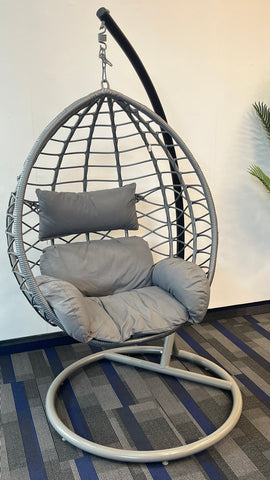 single grey swing egg chair on grey and blue carpet and white wall.