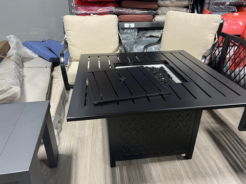 Black Square aluminum firepit, in front of two swivel chairs.