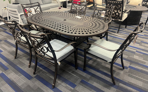 7-piece dark cast-aluminum dining set with ornate chair design, and weave table design.  On blue and Grey carpet