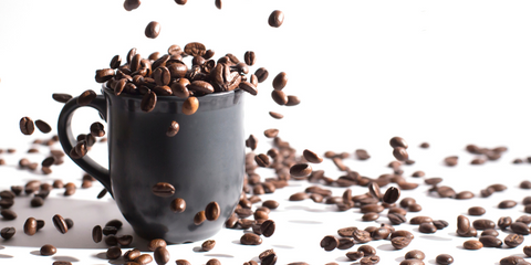 coffee beans falling into a black mug