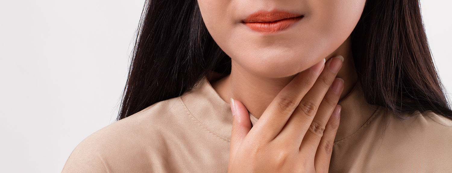 Woman putting her hand to sore throat