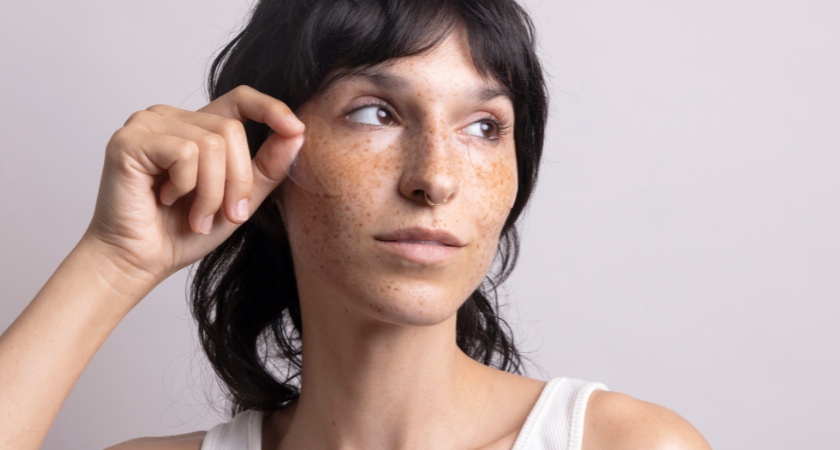 Brighter Days Red Algae + Avocado Biodegradable Eye Masks, model holding up mask to face 