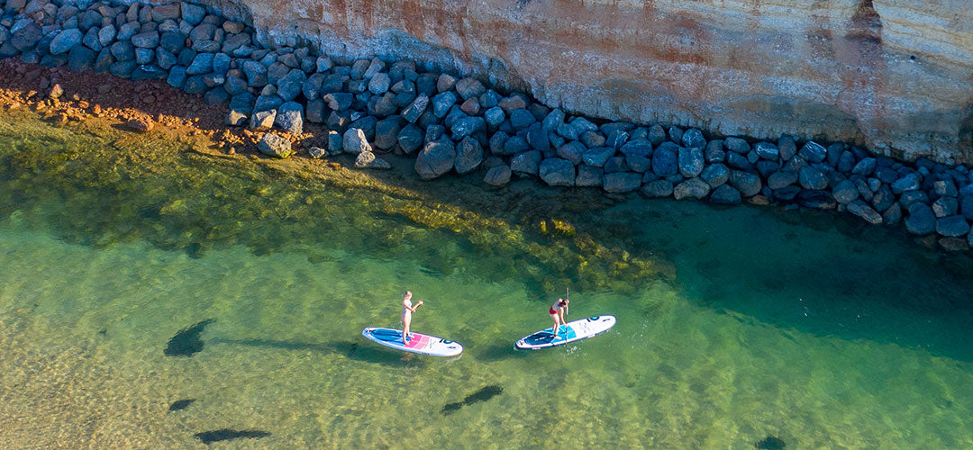 Two girls stand up paddleboarding in Port Noarlunga in South Australia