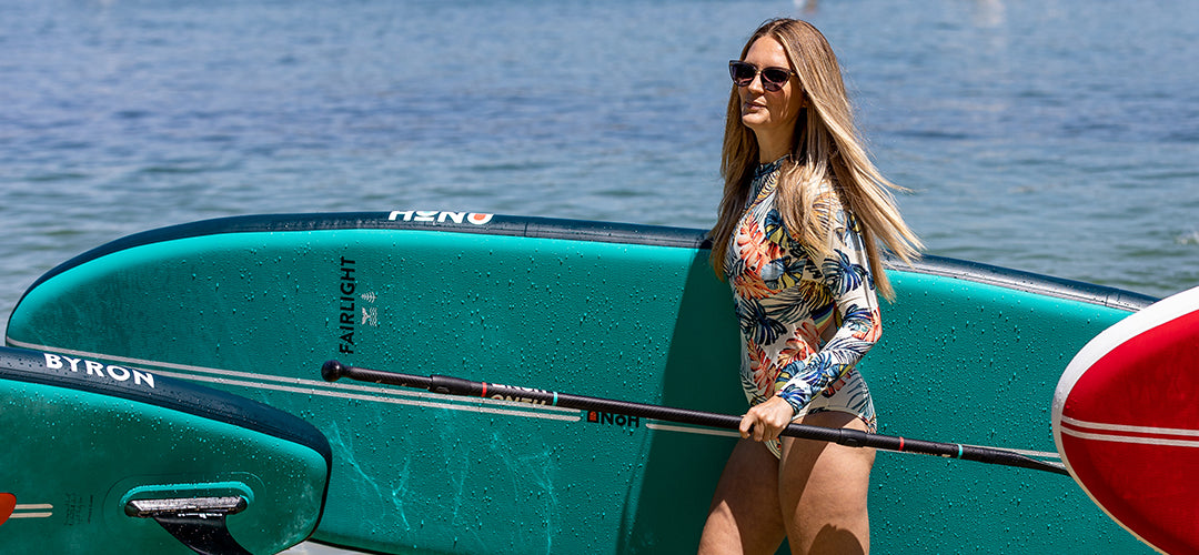 A woman carrying her paddleboard and paddle