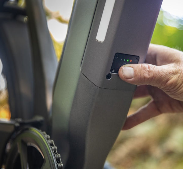 A hand pushing the power button on an electric bike to turn on the electric bike motor.