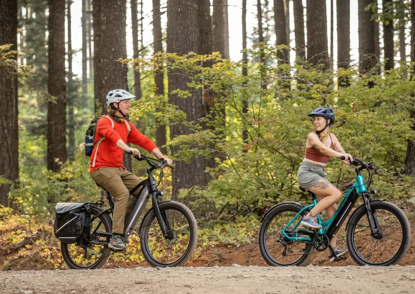 Two people riding on Schwinn electric bikes through nature.