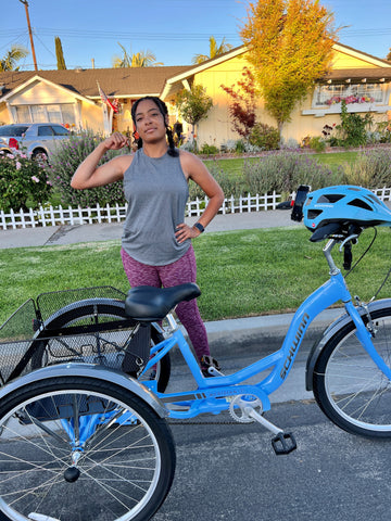 Sydney posing and flexing her muscles next to her trike.