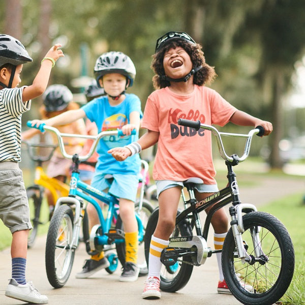 A group of kids wearing bright colored clothes while riding their bikes