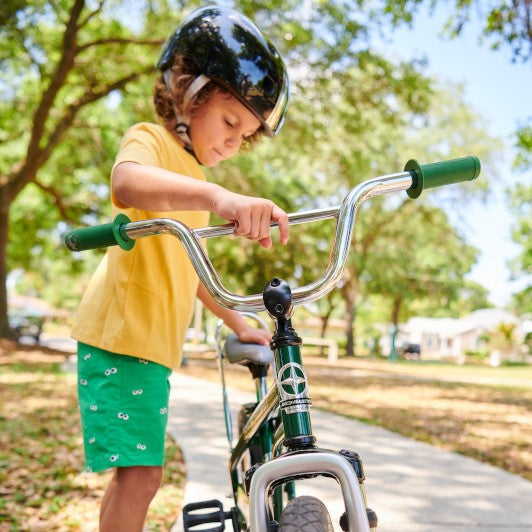 A young boy checking over his green Schwinn bike before going on a bike ride.