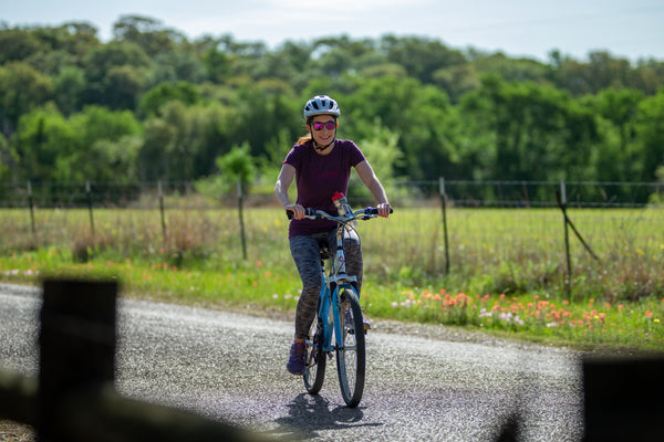 Audrey Wick smiling as rides her hybrid bike by Schwinn down a road.