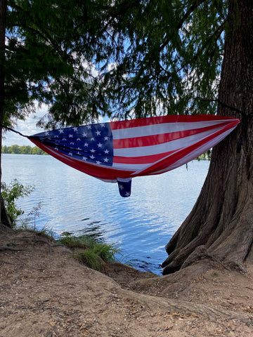American flag hammock blowing in the breeze on Lady Bird Lake to show that our hammocks are large enough for up to 2 adults to sit in comfortably