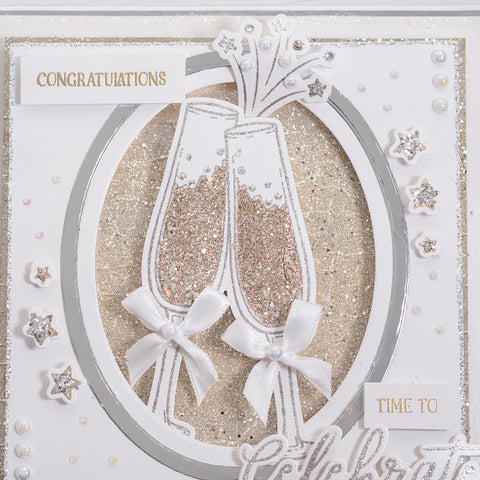 Learn how to make your own Champagne Glasses congratulations greetings card using our free card-making tutorial which is perfect for engagements, new jobs or promotions. This stunning white and gold card features glitter embellishment, script font sentiment stamps and beautiful bow details on our new champagne glasses.