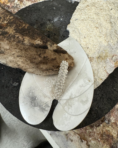 Photo of the dingy silver pieces of the anthurium earrings being supported by chunks of charcoal and solderite, getting ready to be soldered