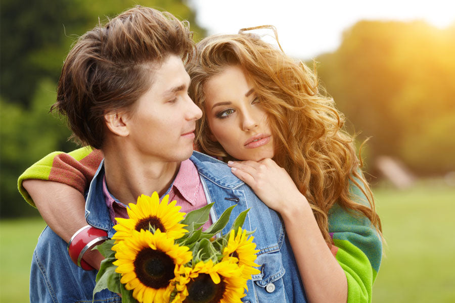 young woman hugging young man in field with sunflowers, first sexual experience story
