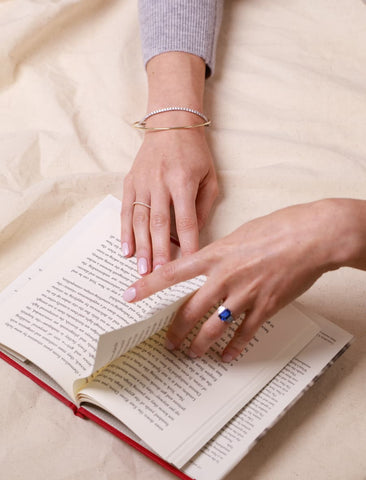 Sapphire ring and diamond bracelet reading a book
