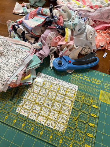 Maria Fisher from Delightfully Quilted, is cutting squares out of baby clothes for a baby quilt