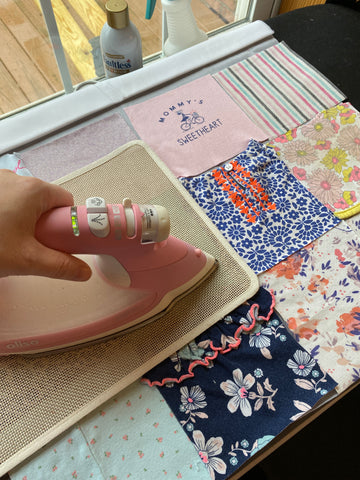 Maria Fisher is ironing stabilizer to the back of the baby clothes for the baby quilt