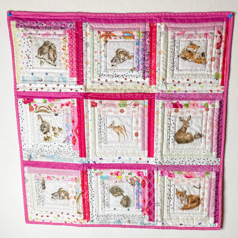 Pink and White print fabrics with center baby animals created into a patchwork baby sized Quilt