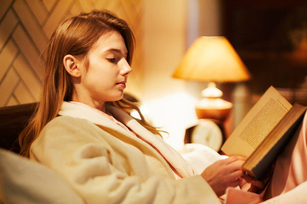 ベッドで本読んでいるガウン姿の女性
