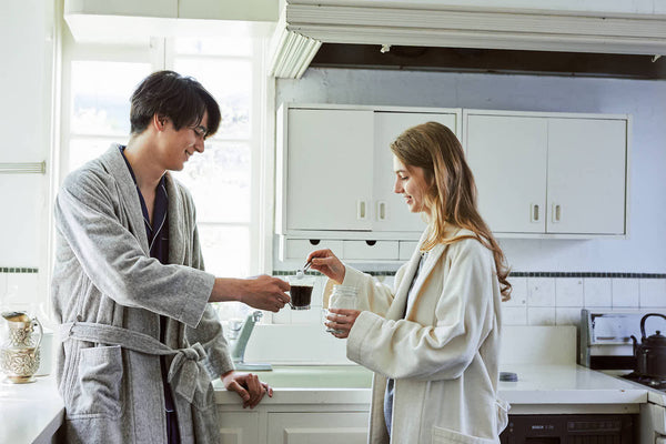 自宅のキッチンでパジャマ姿でコーヒーを楽しむカップル