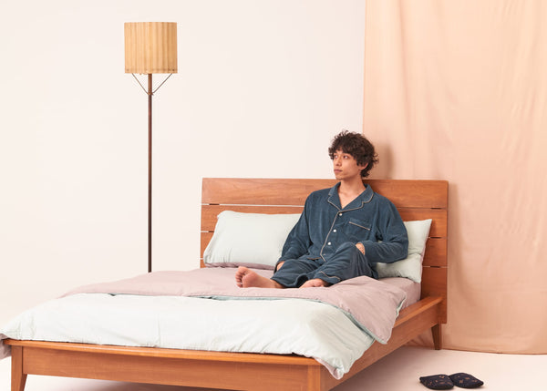 ベッドの上でFoo Tokyoのコットンパジャマ姿の男性