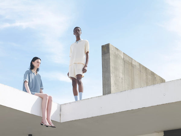 ポロシャツを着て屋根上に座る女性と立っている男性