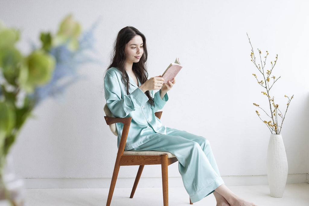 Foo Tokyoシルクパジャマ ミントグリーンを着て椅子に座りながら本を読む女性