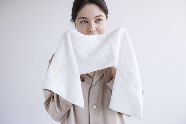 女性がタオルで顔を拭く