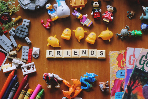 友達　テーブルの上にはおもちゃがfriendの言葉に並べられ、漫画や玩具が散乱している。