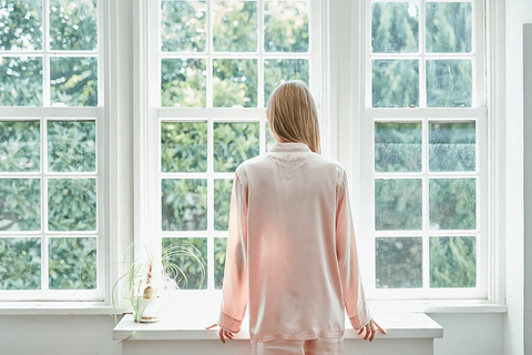 女性　ルームウェア　窓の外を眺めるパジャマ姿の女性