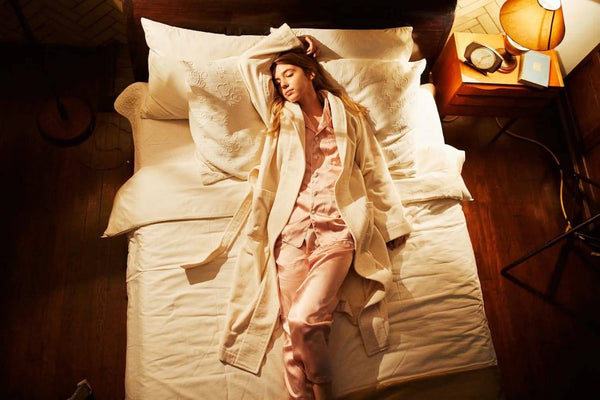 ベッドの上でシルクパジャマとガウンを着ている女性