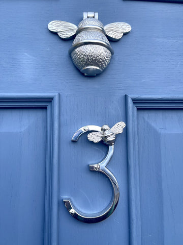 A picture of a brass door number on a blue door.