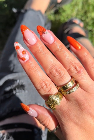 A close-up view of Harvest Glam-inspired nails featuring rich, jewel-toned colors, intricate designs resembling autumn fruits and vegetables, and a touch of metallic gold accents. The perfect fall-inspired manicure for a touch of opulence. #HarvestGlam #FallNailArt