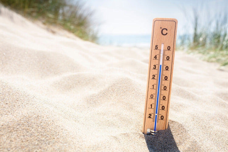 Termometer på en sandstrand med høj temperatur som kan medvirke til at man får solstik