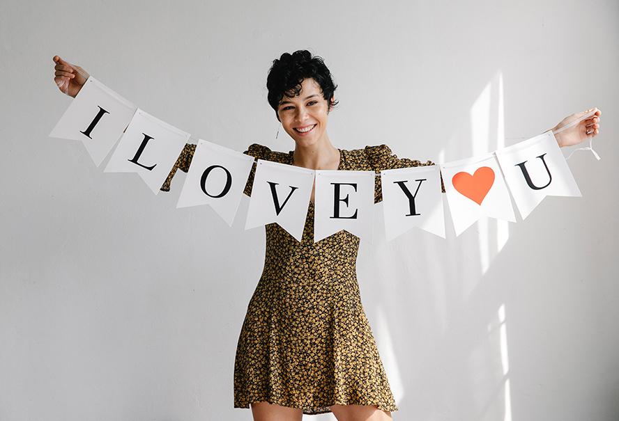 A woman smiling, holding a banner that reads "I Love U".