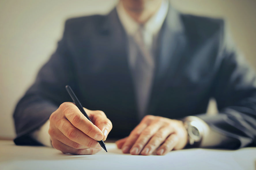 A professional man in a suit writing a letter.