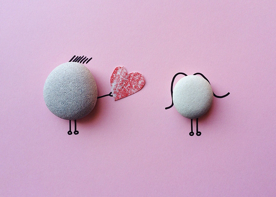 A cute drawing of one rock giving another rock a heart.
