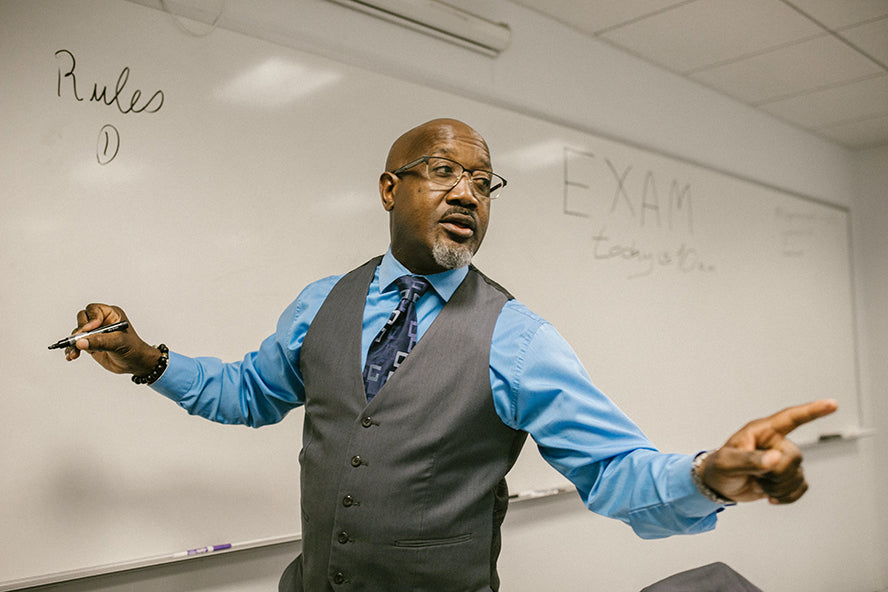 Close up on a teacher speaking and writing on the board.