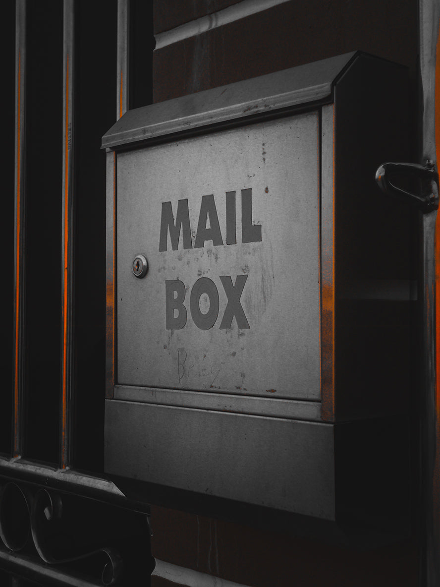 A black metal mailbox hanging on the side of a building.