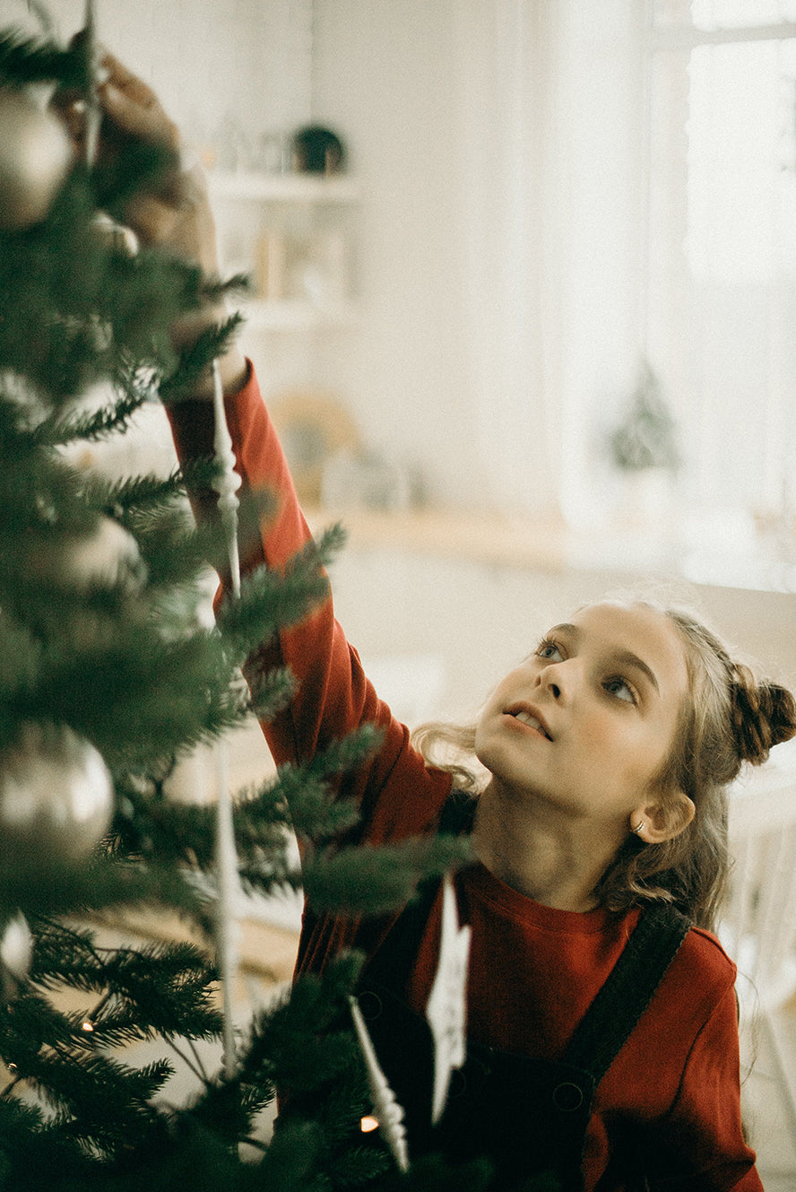 Girl putting up a star on a Christmas tree.