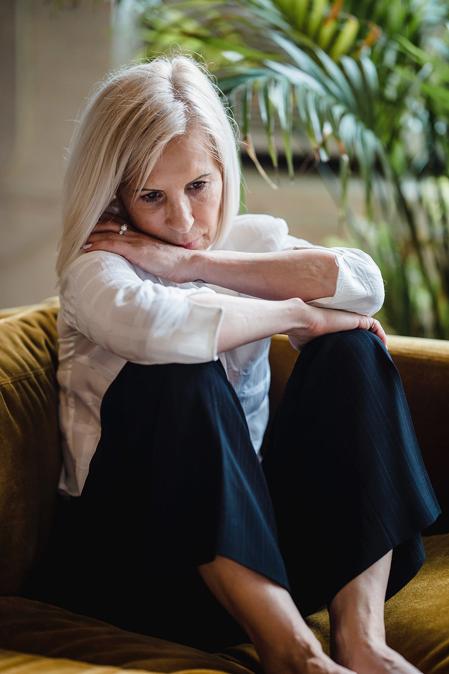 A sad woman sitting on her couch.