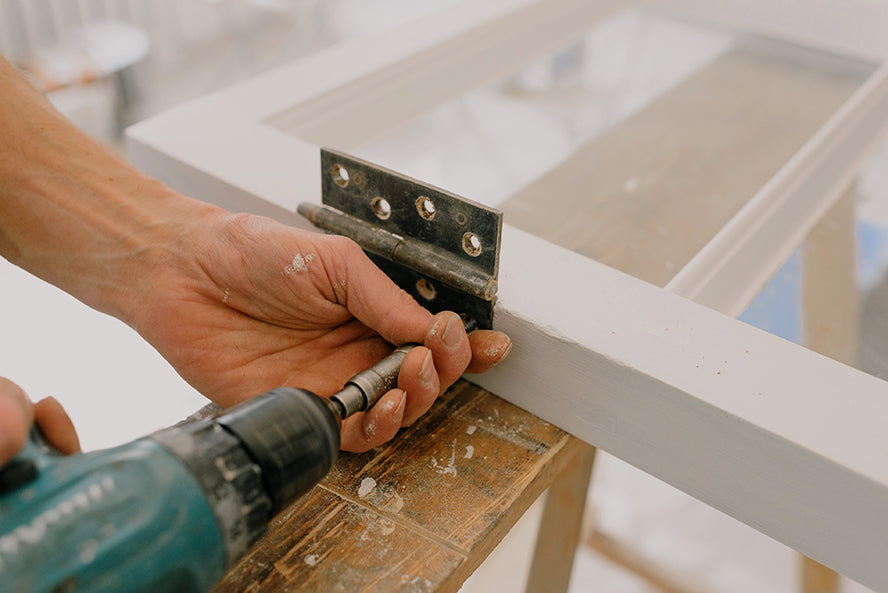 A worker attaching hinges to a door.