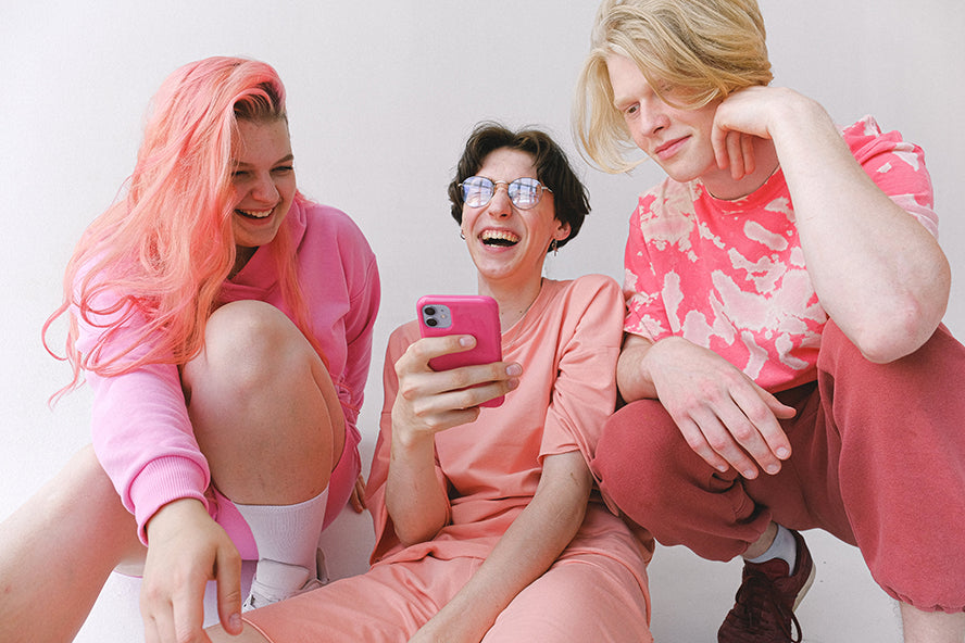 A group of friends smiling at a cellphone.