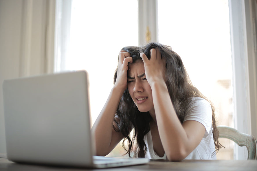 A woman staring frustrated at her laptop.