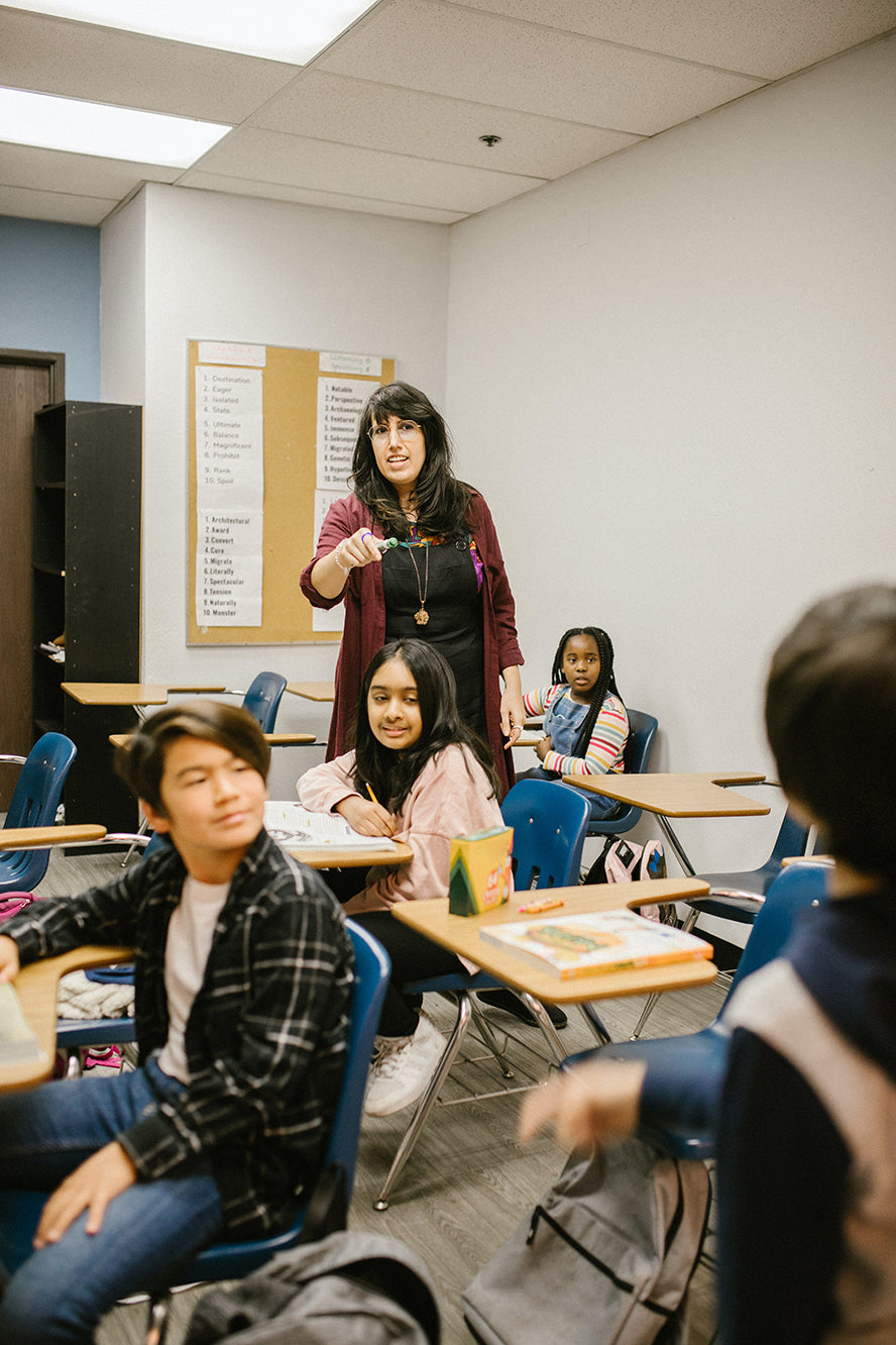 Teacher leading a classroom of children.