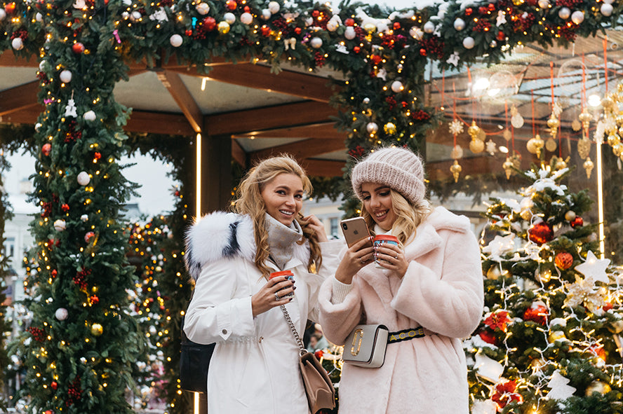 Women sending each other holiday messages on their phones.